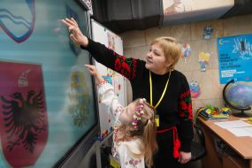 A teacher with a girl near an interactive board in an underground kindergarten in the Kharkiv metro
