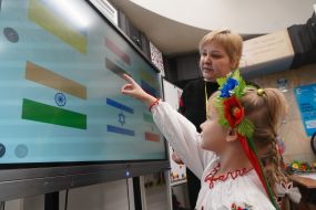 A teacher with a girl near an interactive board in an underground kindergarten in the Kharkiv metro
