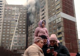 Women and a man with a girl near a house damaged by a rocket attack in Kyiv