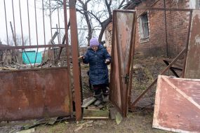 An elderly woman near a dilapidated house in the city of Vovchansk