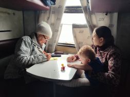 Пожилая женщина и женщина с ребенком на руках в вагоне эвакуационного поезда в городе Покровск