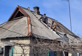 Local residents restore the roof of a house damaged after shelling