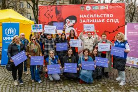 Participants of "Walk in Different Shoes for Gender Equality" hold banners