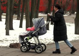 A woman carries a child in a stroller in a park in Kyiv