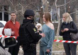 A policeman talks to a girl holding a dog at the impact site after a rocket strike in Kharkiv