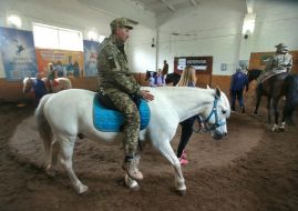 Українські військовослужбовці їдуть на конях під час сеансу іпотерапії на Київському іподромі
