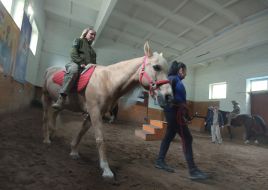 Українські військовослужбовці їдуть на конях під час сеансу іпотерапії на Київському іподромі