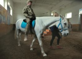 Український військовослужбовець їде на коні під час сеансу іпотерапії на Київському іподромі