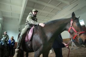Українські військовослужбовці їдуть на конях під час сеансу іпотерапії на Київському іподромі