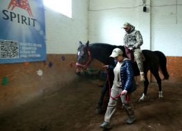 Український військовослужбовець їде на коні під час сеансу іпотерапії на Київському іподромі