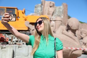 A woman takes a selfie on a mobile phone against the background of the dismantling of the monument "Pereyaslavska rada"