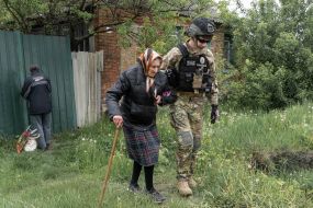 A policeman accompanies an elderly woman during the evacuation of civilians from war zones in the city of Vovchansk