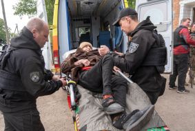 Волонтеры грузят пожилую женщину в автомобиль скорой помощи во время эвакуации мирных жителей недалеко от города Волчанск