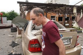 A man near his broken car after the explosion of a Russian UMPB D-30 projectile in Kharkiv