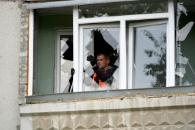 Employee of the communal service removes broken glass from the window of apartment after the explosion of a Russian UMPB D-30 projectile in Kharkiv