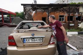 A man near his broken car after the explosion of a Russian UMPB D-30 projectile in Kharkiv