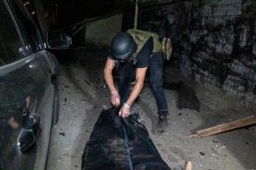 Rescuer put the body of the deceased in a black bag on the rubble of an apartment building in Kharkiv