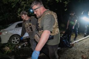 Ritualists carry the body of a dead man in a black bag on the rubble of a rich apartment building in Kharkov