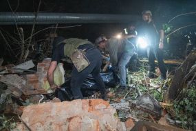 Rescuers put the body of the deceased in a black bag on the rubble of an apartment building in Kharkiv