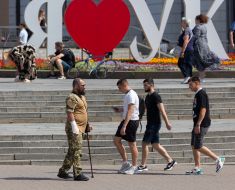 Молоді люди проходять біля військового
