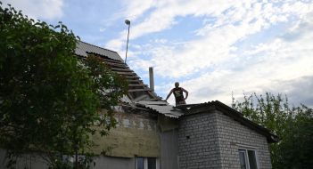 Мужчина на поврежденной в результате взрыва российского боеприпаса крыше дома в Харькове