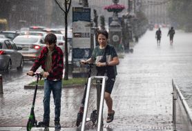 Teenagers with electric scooters in the rain in the center of Kyiv