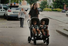 A woman carries two children in a stroller on the street in Cherkasy