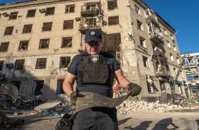 A policeman holds a piece of debris near a destroyed residential building in Kharkiv