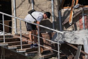 A man sweeps up debris near a damaged house in Kharkiv