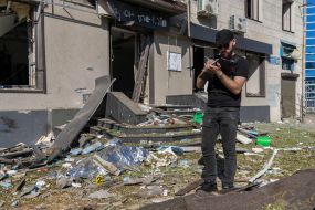 A police investigator records war crimes near a destroyed residential building in Kharkiv
