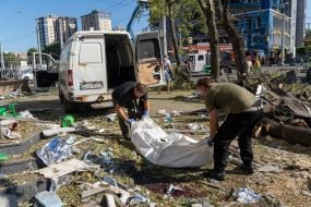 Rescuers carry the body of a deceased person in a bag near an apartment building that was destroyed by shelling in Kharkiv