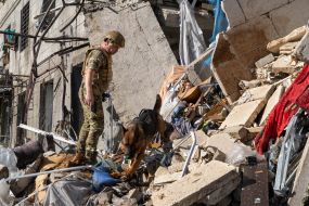 A rescuer with a dog searches for people under the rubble of an apartment building in Kharkiv