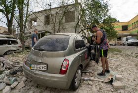 Men inspect a car after guided aerial bombs hit Kharkiv