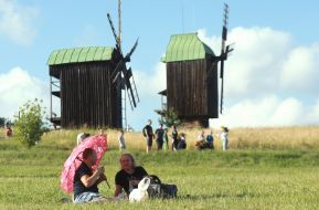 People rest on a lawn with mills in the background