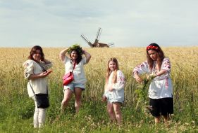 Young women on the background of a wheat field and a mill
