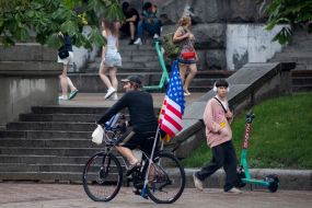 Чоловік на велосипеді з американським прапором