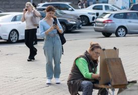 A woman photographs an artist at work on Independence Square in Kyiv