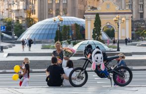 Продавщица предалагает молодой паре купить у нее цветы