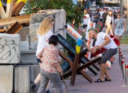 A man paints anti-tank hedgehogs in the colors of the Ukrainian flag on the street in Kyiv