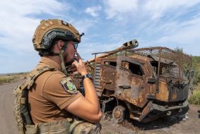 A serviceman near burnt military equipment