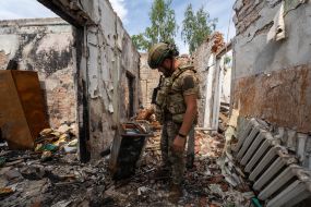 A serviceman inspects the destruction caused by Russian shelling