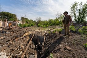 A serviceman inspects the destruction caused by Russian shelling