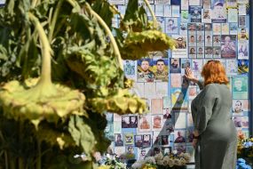 People carry flowers to the Memorial Wall on Mykhailivska Square on the Day of Remembrance of Fallen Defenders of Ukraine