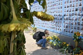 People carry flowers to the Memorial Wall on Mykhailivska Square on the Day of Remembrance of Fallen Defenders of Ukraine