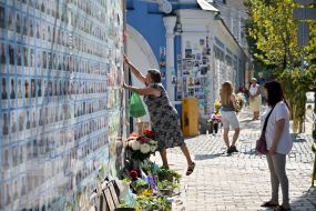 People carry flowers to the Memorial Wall on Mykhailivska Square on the Day of Remembrance of Fallen Defenders of Ukraine