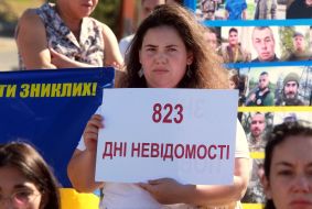 Женщина, держащая плакат с надписью "823 дня неизвестности"