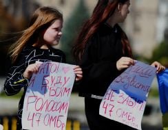 Женщина и девочка держат плакаты с информацией о пропавшем без вести муже и отце