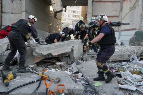 Rescuers lift a concrete slab on the ruins of a residential building in Kharkiv