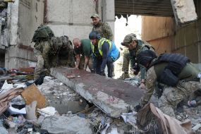 Rescuers lift a blood-stained concrete slab on the ruins of a residential building in Kharkiv