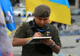 A serviceman makes an inscription on a frame with a portrait of a fallen soldier on the Independence Square in Kyiv